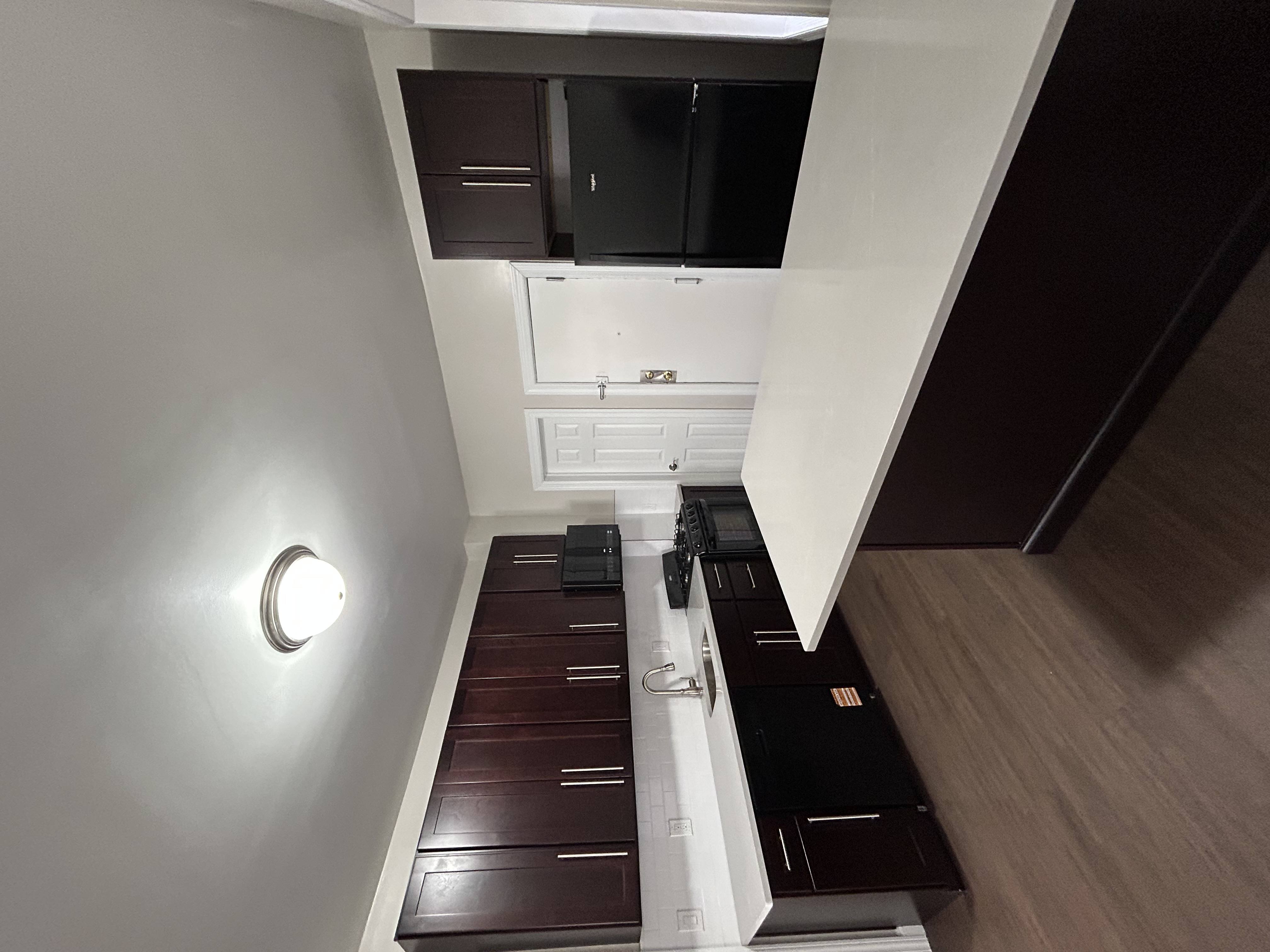 A modern kitchen with dark wood floors and white walls.